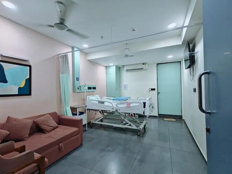 Attendant sofa and patient bed in the deluxe room at Pluto Hospital, Himatnagar