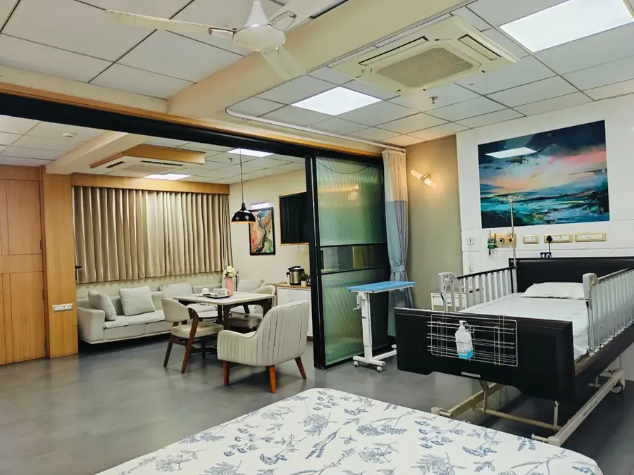 Patient bed and sitting area in the VIP suite at Pluto Hospital, Himatnagar